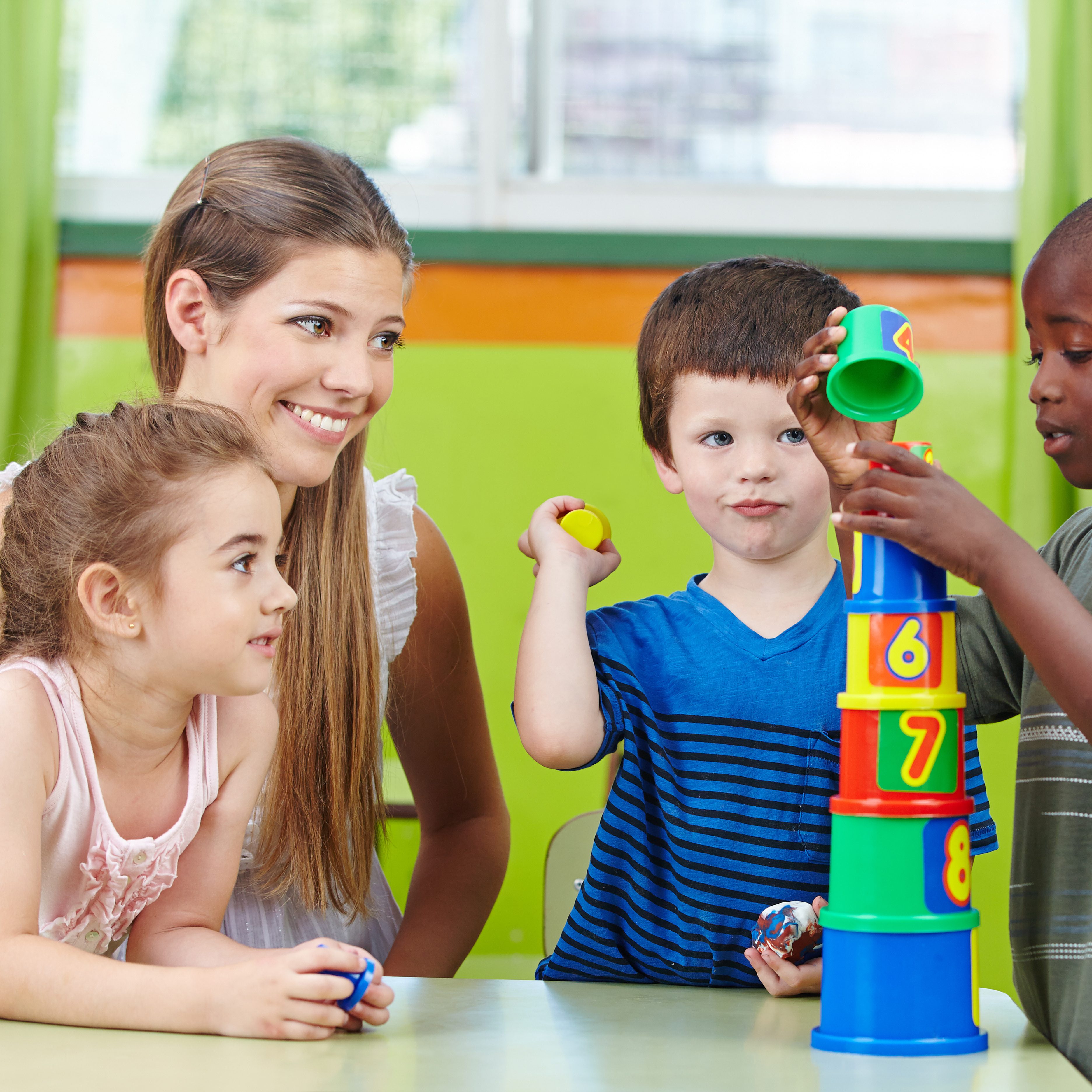Children with nursery teacher building tower in a kindergarten group